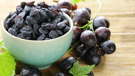 Bowl of raisins next to grapes